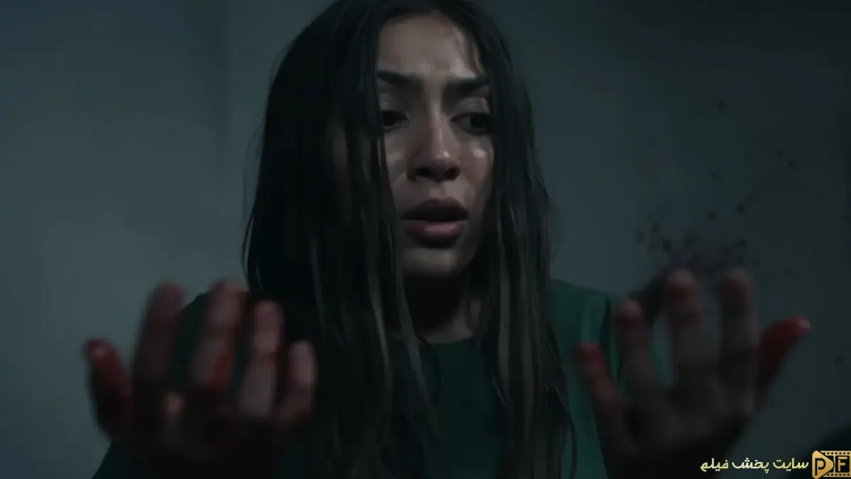 هانا جان کامن در نمایی پرتنش از فیلم خانه امن (Safe House) - چهره او وحشت‌زده است و به دست‌های خونی خود نگاه می‌کند.