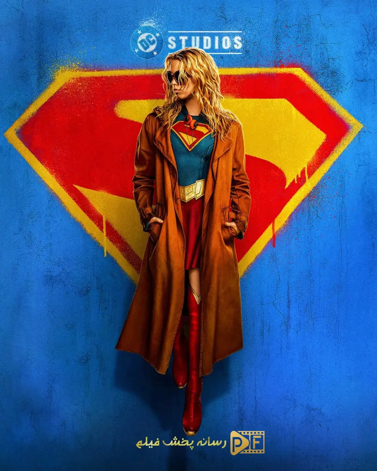 پوستر رسمی فیلم سوپرگرل Supergirl: Woman of Tomorrow؛ میلی آلکاک با عینک دودی و کت بلند در مقابل لوگوی گرافیتی خاندان ال و دیسی استودیوز