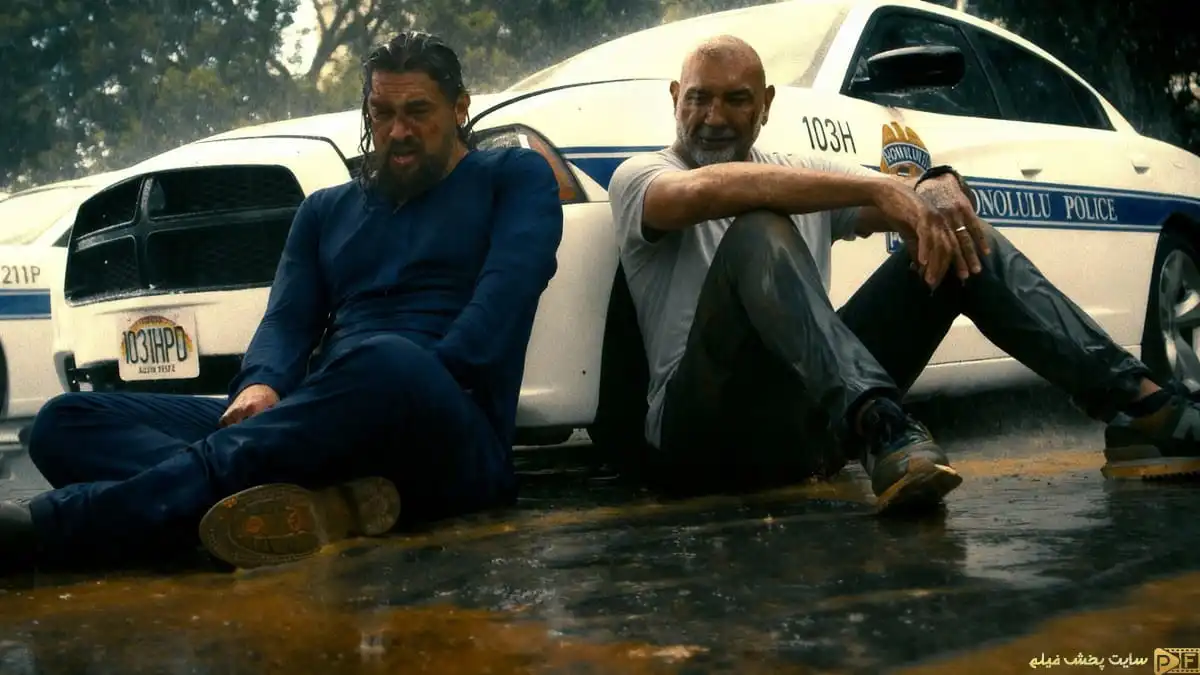 دانلود فیلم The Wrecking Crew 2026؛ صحنه کمدی استراحت بازیگران کنار ماشین پلیس زیر باران